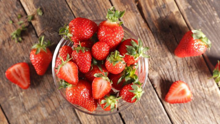 Man erkennt Erdbeeren in einer Glasschüssel.
