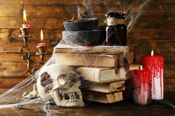 Man erkennt eine Halloween Deko mit Totenköpfen, Spinnennetzen und alten Büchern.