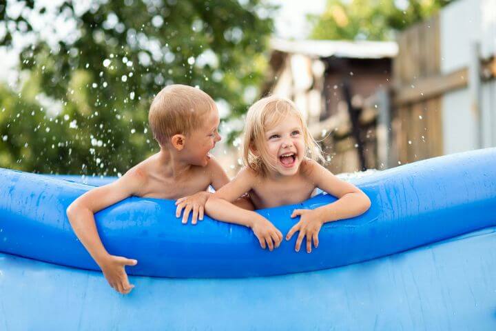 Zwei lachende Kinder in aufblasbarem Schwimmbecken