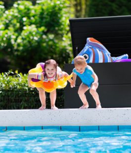 two kids jumping into the pool / with grey garden box behind them / steel garden box
