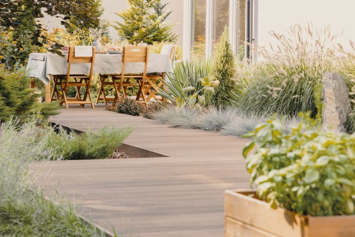 Terrassengestaltung: Holzweg mit Gräsern führt zu einer Terrasse modern mit Gartenmöbeln
