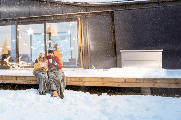 Wintergarten Aufwertung: junges Paar sitz in Decke gehüllt auf der Terrasse während es schneit
