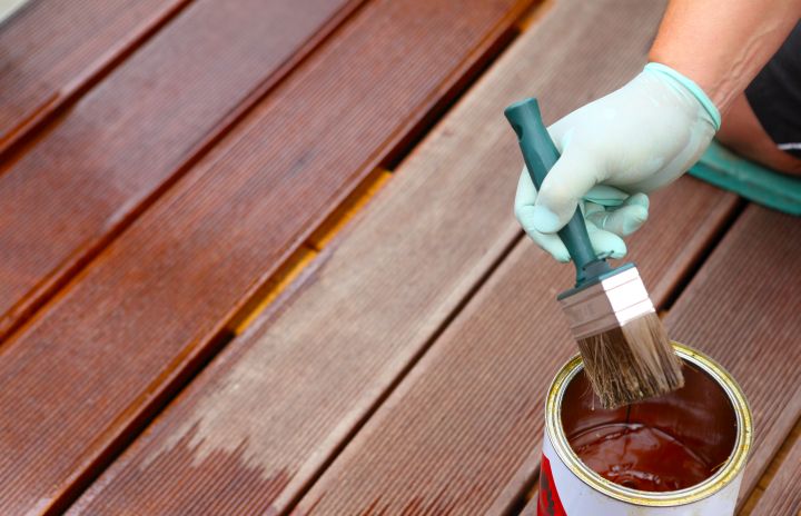Hand streich Terrassenboden mit Pflegeöl um Terrasse winterfest machen