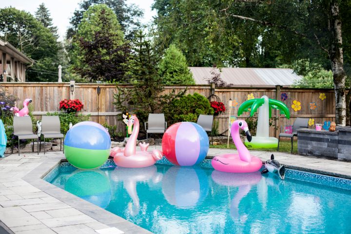 Zwei Wasserbälle, eine aufgeblasene Palme und ein Flamingo schwimmen in einem Pool