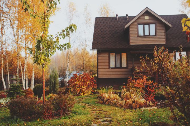 Country-Haus aus Holz umgeben von herbstlichem Garten