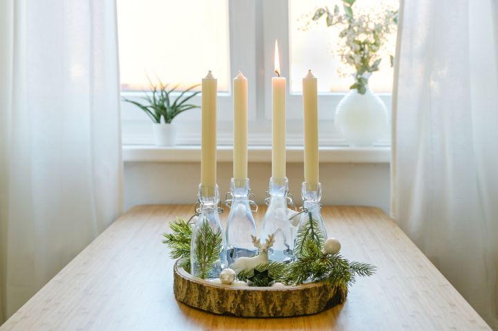 Alternativer Adventskranz mit vier Kerzen auf einem Holzbrett